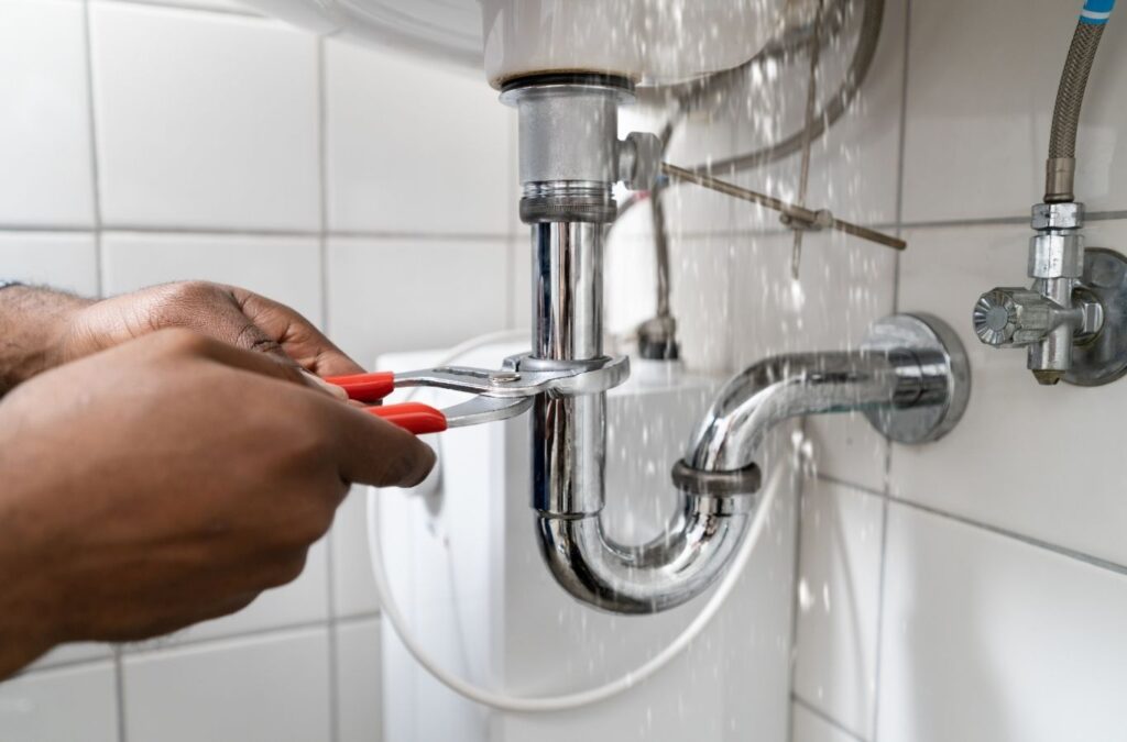 Plumber repairing leaking kitchen sink plumbing during a routine service visit in Mississauga home