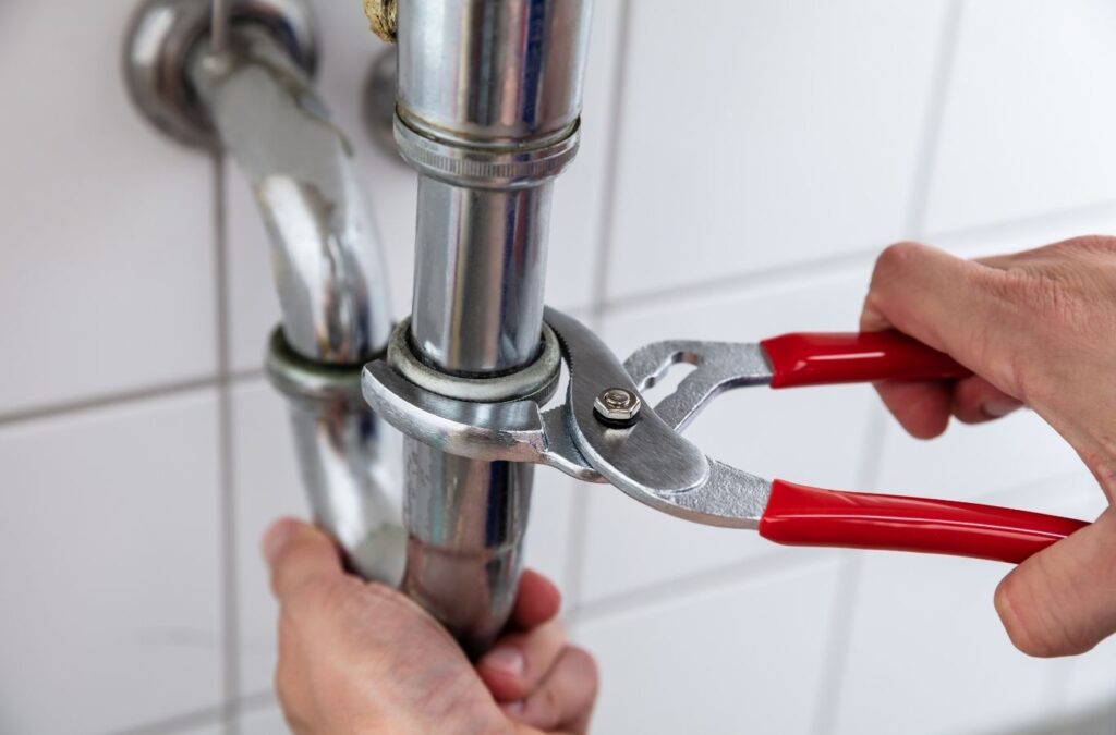 Experienced plumber inspecting exposed piping and valves with diagnostic tools in utility room. Plumber near me.
