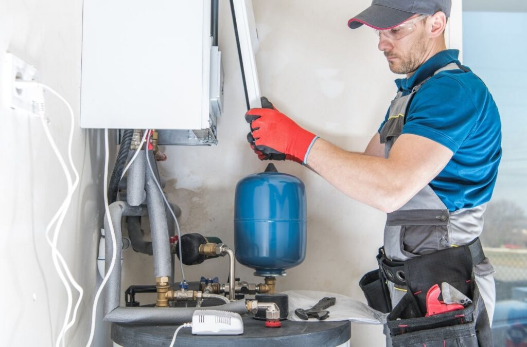 Technician repairing residential water heater after hot water failure in basement