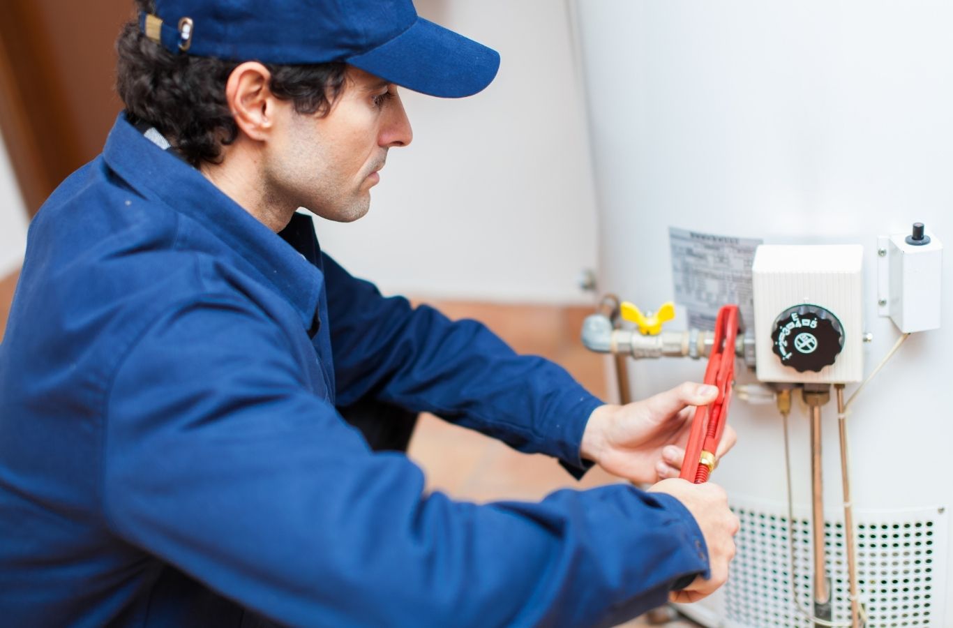 Skilled technician diagnosing water heater controls with testing tools in utility room