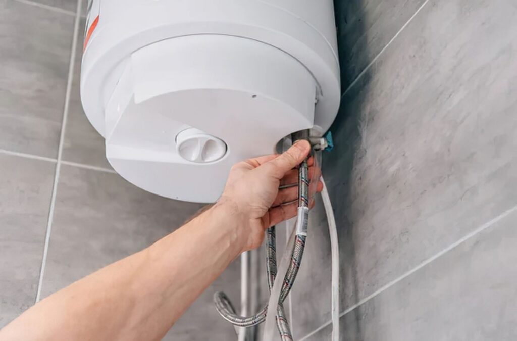 Plumber repairing leaking water heater beside finished basement storage area