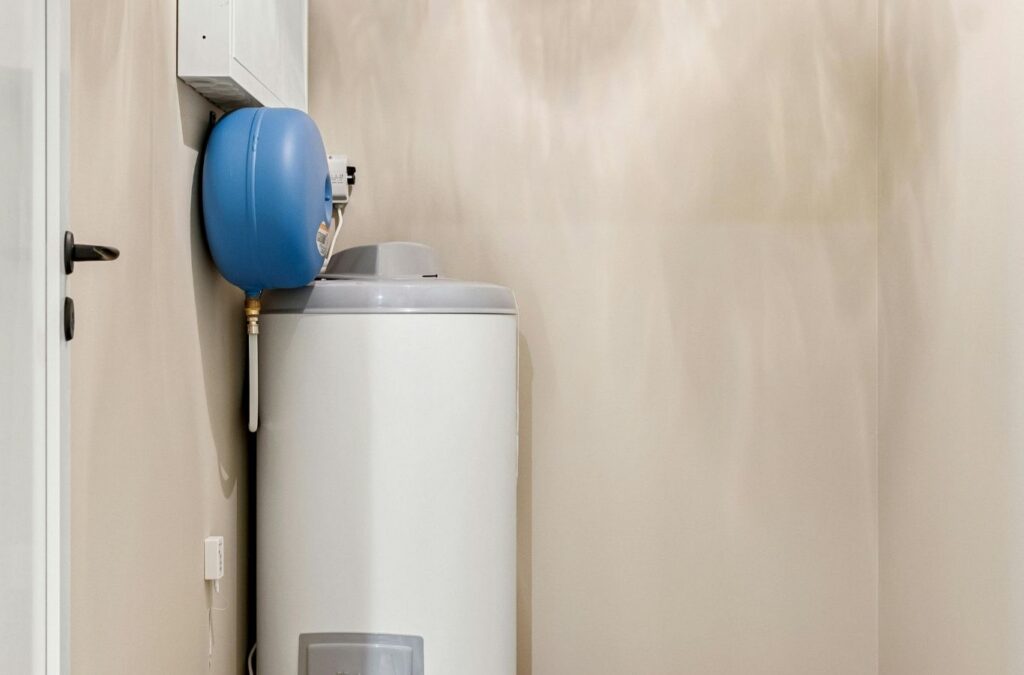 Experienced plumber testing water heater components with meter beside residential tank