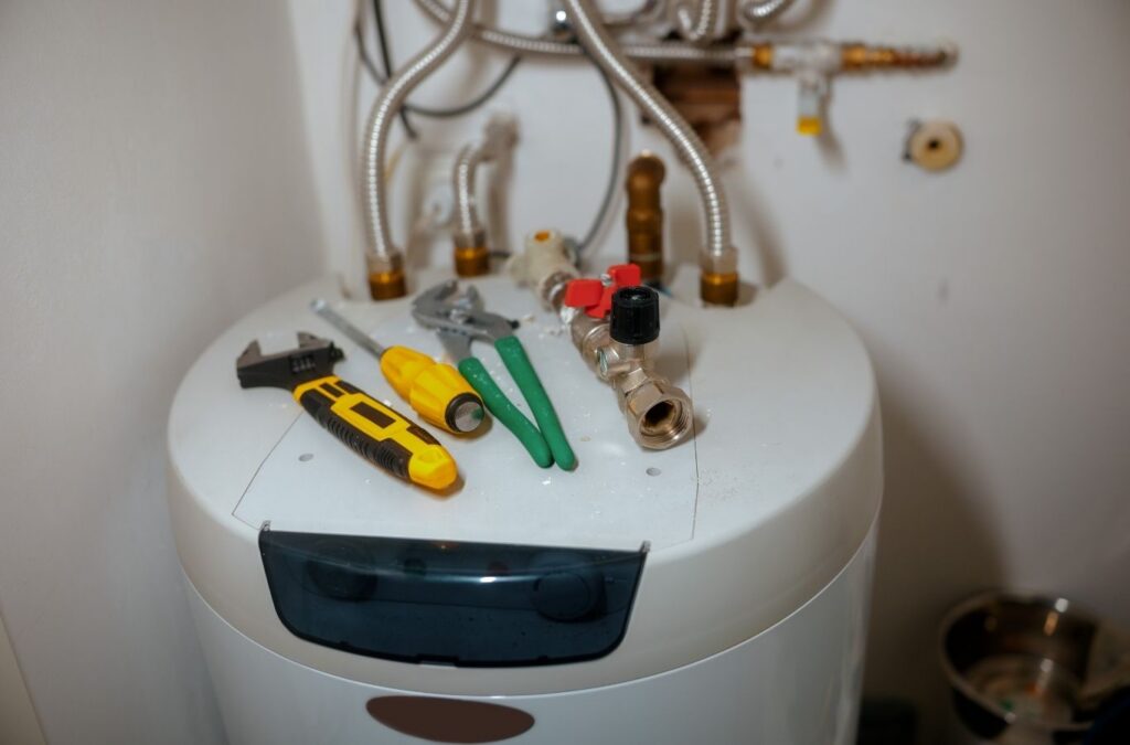 Experienced plumber testing thermostat and heating components on residential water heater system. Water Heater Repair near me.