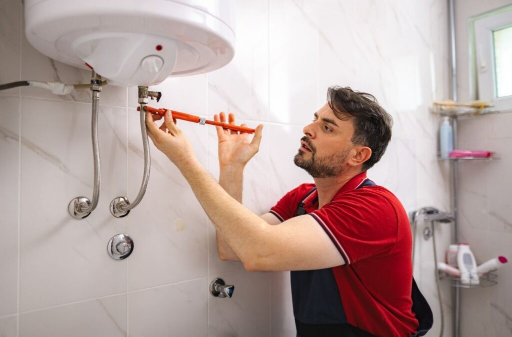 Technician repairing residential water heater after morning hot water loss in Ajax basement