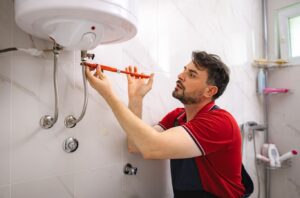 Technician repairing residential water heater after morning hot water loss in Ajax basement